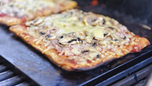 Varm pizza bagt på en bagesten i en kuglegrill