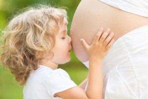 Barn kysser maven på gravid kvinde