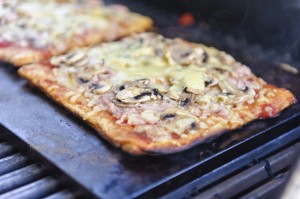 Varm pizza bagt på en bagesten i en kuglegrill