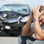 Mand sidder med hovede i hænderne efter ulykke med bils som er totalskadet