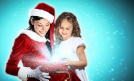Kvinde i julemandskostume ser på en pakke til en lille pige