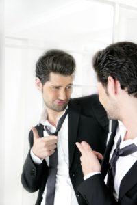 Mand i jakkesæt ser på sig selv i et spejl