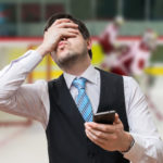 Ulykkelig mand med smartphone foran ishockey kamp - ludomani og gambling